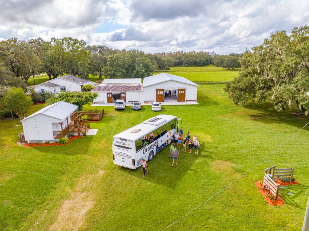Tour bus is delivering the wedding party and guests to the Heart D Farm. This aerial photo shows the beauty of the farm with an aerial shot. The white and stained buildings against the green backdrop is stunning!